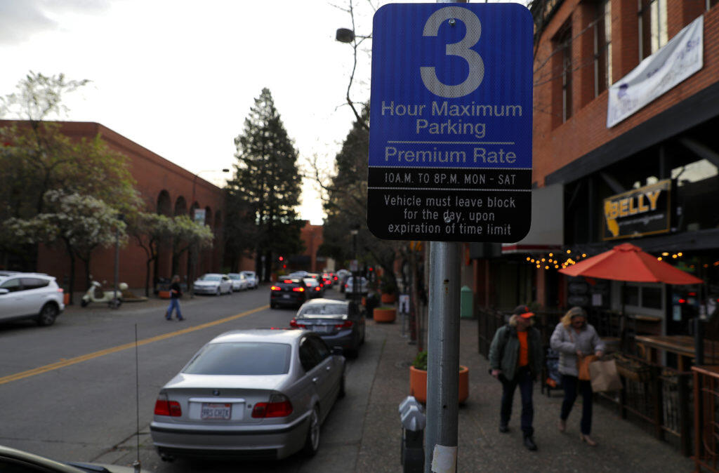 A sign on 4th Street informs the public about the paid parking enforcement times, which now extend to 8 p.m., in Santa Rosa on Friday, January 26, 2018.   (Christopher Chung/ The Press Democrat)