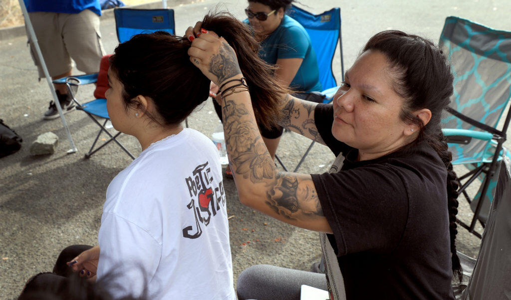 Lindsay Rodriguez puts her niece Jazmyn Garcia’s hair in a ponytail, Tuesday, July 9, 2019 at Lake Mendocino at they keep vigil with other family members for Vincent Soto, 40, who drowned in Lake Mendocino in early June, but has still not been recovered.  (Kent Porter / The Press Democrat) 2019