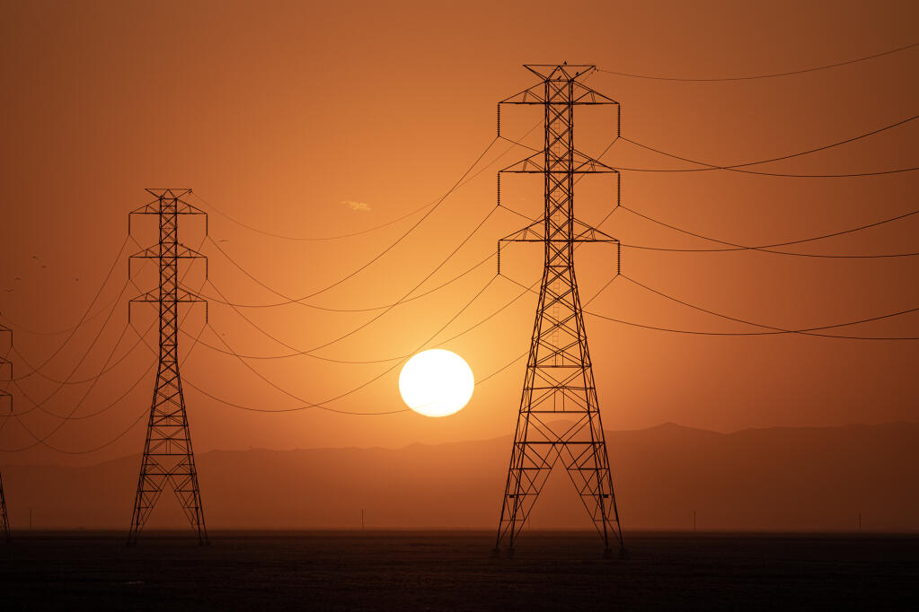 The sun sets behind a row of electric towers in Fresno County on Sept. 6, 2022. Photo by Larry Valenzuela, CalMatters/CatchLight Local