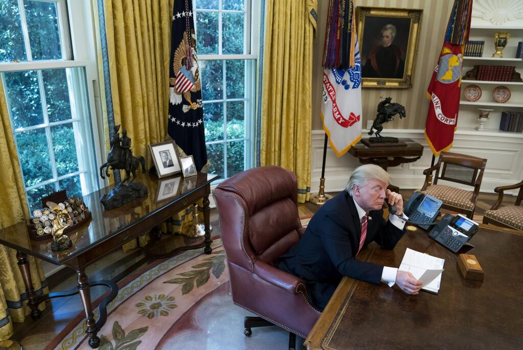 FILE -- President Donald Trump speaks on the phone in the Oval Office with a photo of his father, Fred C. Trump, behind him in the White House in Washington, June 27, 2017. President Trump received today's equivalent of over $400 million from the real estate empire of his father. (Doug Mills/The New York Times)