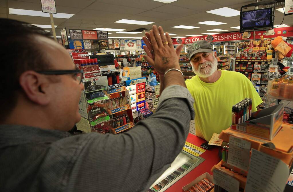 Corky Cramer of Santa Rosa exchanges a high five with Brij Desor, left, the owner of Octagan C market on Lewis Road in Santa Rosa after purchasing Mega Millons lotto tickets, Monday Oct. 22, 2018. This was the first time Cramer has ever bought a Mega Millions ticket. (Kent Porter / The Press Democrat) 2018