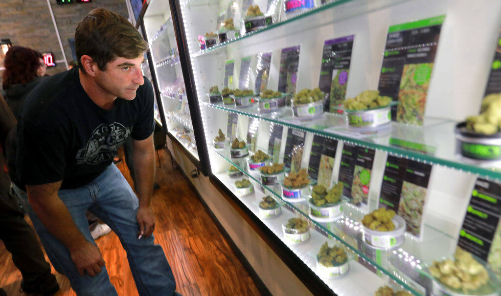 Jason Conte of Santa Rosa looks through the selection of flowers on the first day legal recreational marijuana sales in Sonoma County at Mercy Wellness of Cotati on Monday morning, Jan. 1, 2018. (photo by John Burgess/The Press Democrat)