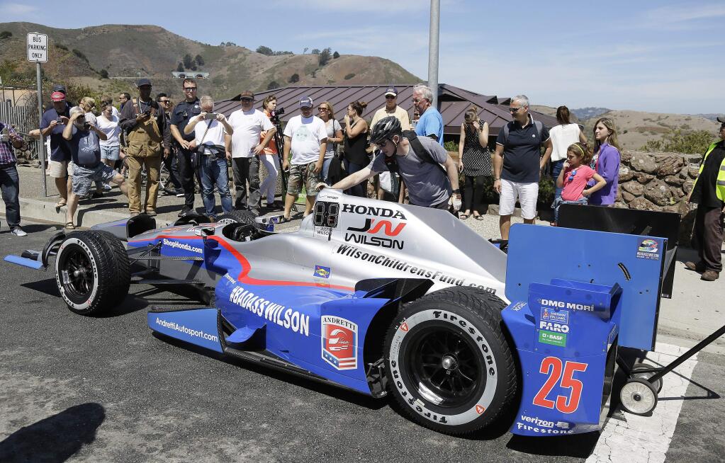 People stop to view Justin Wilson's No. 25 IndyCar after Marco Andretti drove it in his honor in a motorcade over the Golden Gate Bridge, Thursday, Aug. 27, 2015, in Sausalito, Calif. Wilson, of England, died Aug. 24 from injuries sustained at Pocono Raceway. The motorcade of IndyCars and safety vehicles were also delivering the Astor Cup trophy to Sonoma Raceway, the site of this weekend's championship-deciding Grand Prix of Sonoma. (AP Photo/Eric Risberg)