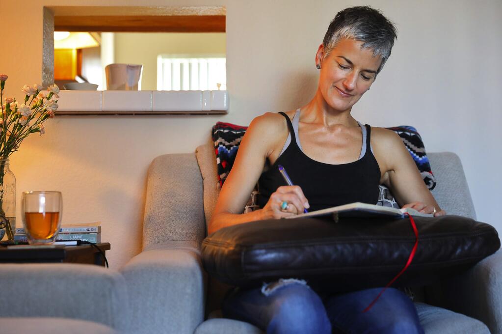 Danielle Bryant, who lost her home in Coffey Park to the wildfires last October, writes in her apartment in Santa Rosa on Friday, June 22, 2018. Bryant took a writing workshop for people affected by the fire, put on by The Santa Rosa Center for the Arts. Bryant finds writing about her experience cathartic.(Christopher Chung/ The Press Democrat)