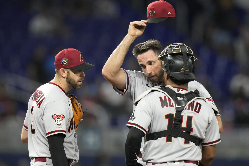 Arizona Diamondbacks starting pitcher Madison Bumgarner, center, stands on the mound with third baseman Evan Longoria, left, and catcher Gabriel Moreno (14) during the fourth inning of a baseball game against the Miami Marlins, Friday, April 14, 2023, in Miami. (AP Photo/Lynne Sladky)