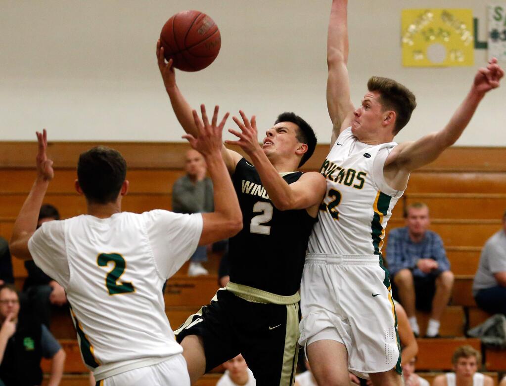 Windsor's Andrew Corcoran (2) draws a foul as he drive to the basket between Casa Grande's Kevin Cadle (22), right, and Dominic McHale (2) during the first half of a boys varsity basketball game between Windsor and Casa Grande high schools in the Brett Callan Memorial Basketball Tourament at Casa Grande High School in Petaluma, California, on Thursday, December 13, 2018. (Alvin Jornada / The Press Democrat)