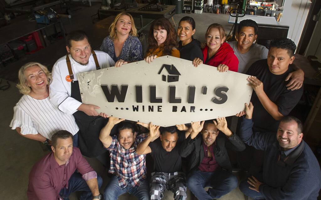 Former employees of Willi's Wine Bar hold the old burnt sign being readied to install in the new location in the Town and Country Shopping Center in northeast Santa Rosa. The crew presently work for other Stark's restaurants until the new location opens. (photo by John Burgess/The Press Democrat) Sept. 20, 2018