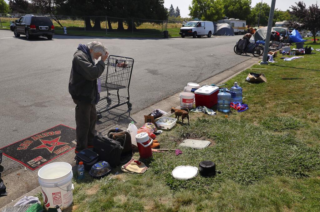 Albert Bruin works on gathering his belongings after the van that he was living in was towed from Challenger Way, in Santa Rosa on Monday, August 13, 2018. (Christopher Chung/ The Press Democrat)