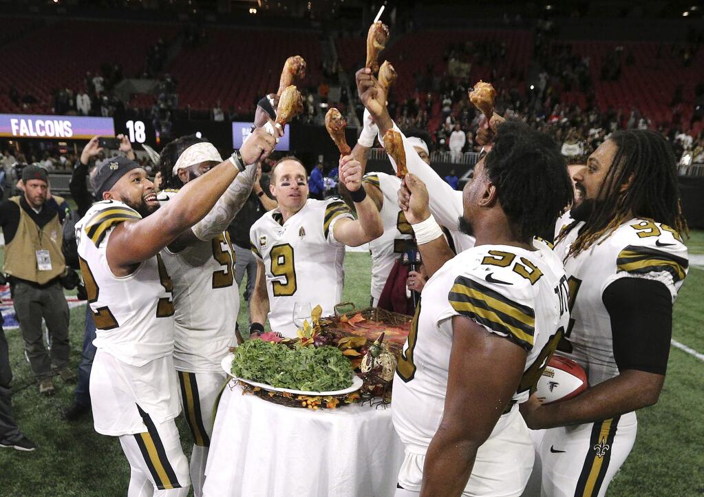 New Orleans Saints quarterback Drew Brees and teammates celebrate a 26-18 victory over the Atlanta Falcons with turkey legs on Thanksgiving Day, Nov. 28, 2019, in Atlanta. The Falcons clinched the NFC South title. (Curtis Compton/Atlanta Journal-Constitution via AP)