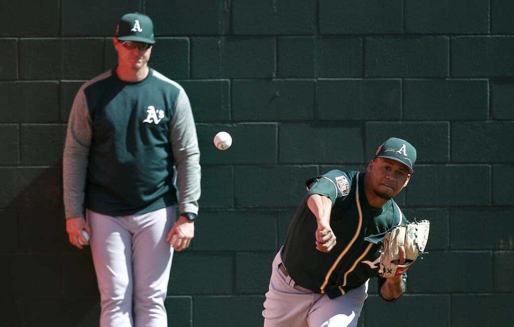 Oakland Athletics relief pitcher Frankie Montas, right, warms up as pitching coach Scott Emerson, left, looks on prior to a spring training baseball game against the Cleveland Indians Tuesday, Feb. 27, 2018, in Goodyear, Ariz. (AP Photo/Ross D. Franklin)