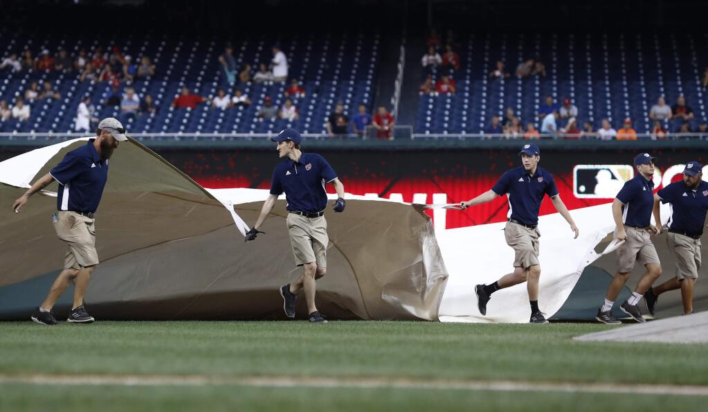 Grounds crew cover the field with a tarp as rain starts to fall before a baseball game between the San Francisco Giants and the Washington Nationals, Friday, Aug. 11, 2017, in Washington. (AP Photo/Carolyn Kaster)