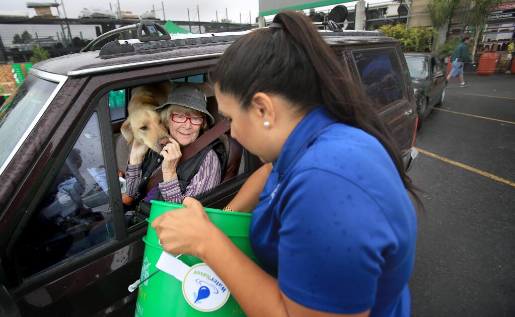 Kathy Johnson of Santa Rosa and her dog Rudy receive a drought kit from Teresa Gudino, a staffer with the City of Santa Rosa water department, on Thursday July 9, 2015 during a drought drive-thru at Friedman's Home Improvement in Santa Rosa. (Kent Porter / Press Democrat)