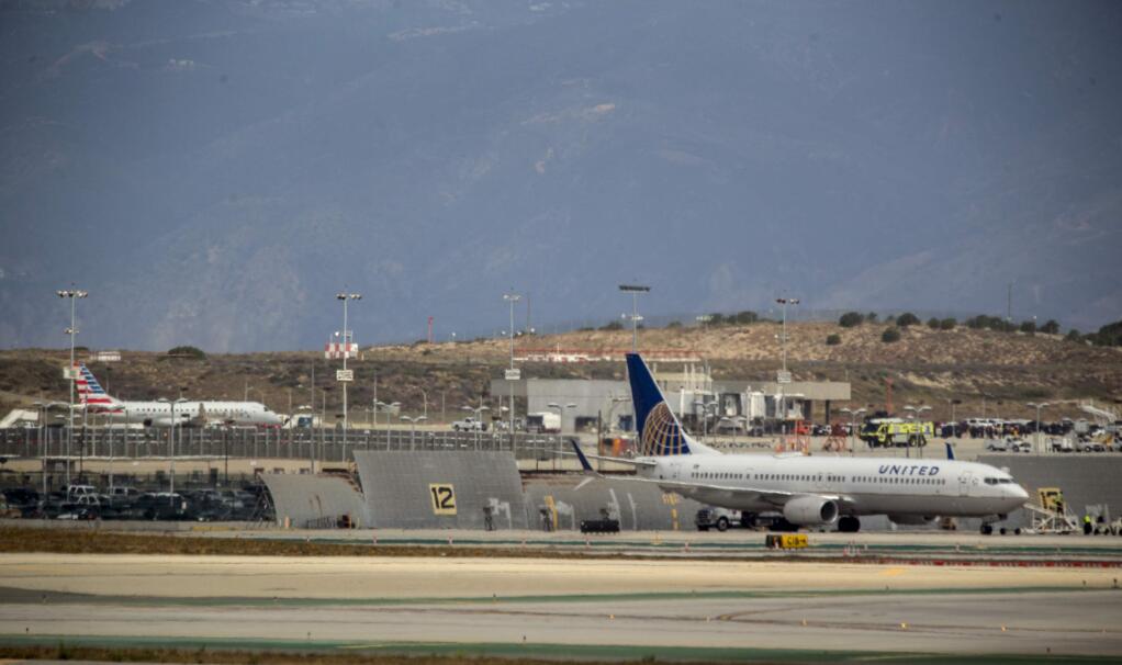 An American Airlines jet, far left, sits on a remote stretch of runway at Los Angeles International Airport Tuesday, May 24, 2016. American Airlines says officials screened the plane as a precaution after a 'non-credible' threat was received about the flight from Houston. Passengers were escorted from the twin-engine regional jet more than an hour after it landed without incident Tuesday morning. A SWAT team with a dog went through the plane. (AP Photo/Damian Dovarganes)
