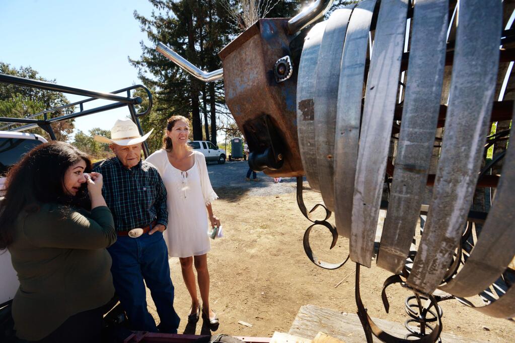 Glyn Evans, 89, center, and Victoria Evans, right, take a moment to look over a sculpture of Angel the cow created in honor of Valerie Evans and designed by Suzette Barker. 'This is the best thing I've ever seen, I love it, this is wild,' said Mr. Evans when the sculpture, welded by artist James Selby, was unveiled at the property on Coffey Lane in Santa Rosa, California where Valerie Evans was killed during the 2017 October Wildfires. September 24, 2018.(Photo: Erik Castro/for The Press Democrat)