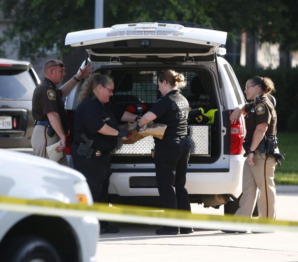 In this Friday, June 24, 2016 photo, Fort Bend County Sheriffs department crime scene members bag a gun for evidence in a shooting at Blanchard Grove and Remson Hollow in Katy, Texas. Officials said a woman shot her two adult daughters - killing one of them at the scene - before she was fatally shot by a responding police officer. (Karen Warren/Houston Chronicle via AP)