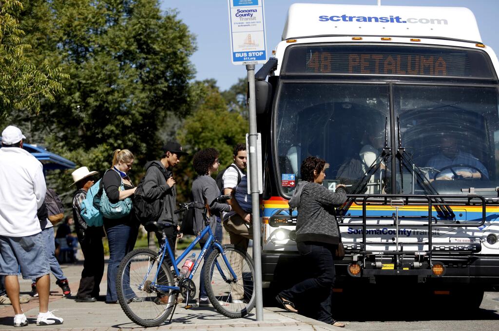 People line up for a Sonoma County Transit bus toward Petaluma at the bus stop on Mendocino Ave. at Pacific Ave. in Santa Rosa, California on Tuesday, September 30, 2014. (BETH SCHLANKER/ The Press Democrat)