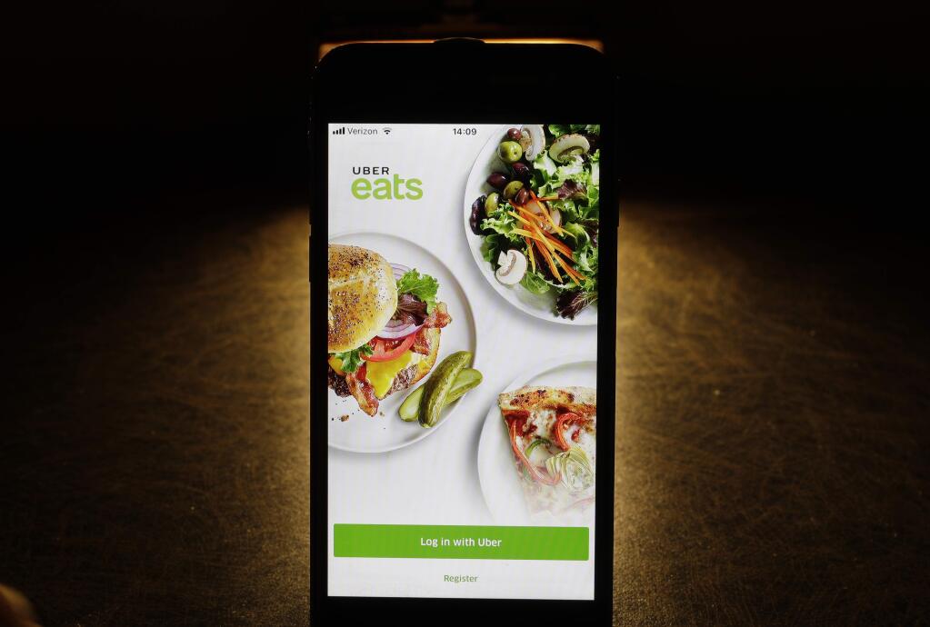 FILE - In this Feb. 20, 2018, file photo shows the Uber Eats app on an iPhone in Chicago. Uber is testing restaurant food deliveries by drone. The company's Uber Eats unit began the tests in San Diego with McDonald's and plans to expand to other restaurants later this year. (AP Photo/Charles Rex Arbogast, File)