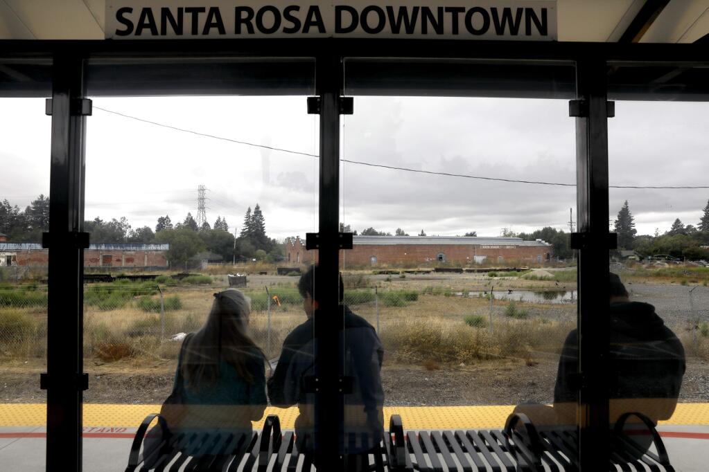 People wait at the downtown SMART station which is across the tracks from a 5-acre piece of property for sale in Santa Rosa on Thursday, October 4, 2018. (Beth Schlanker/ The Press Democrat)