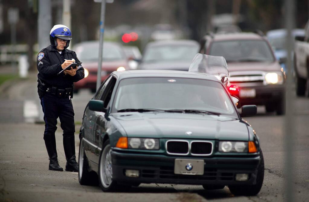 FILE - Santa Rosa police officer Scott Anderson writes a ticket for driving while talking on a cell phone on Third St. in Santa Rosa on Friday afternoon. (PD FILE)