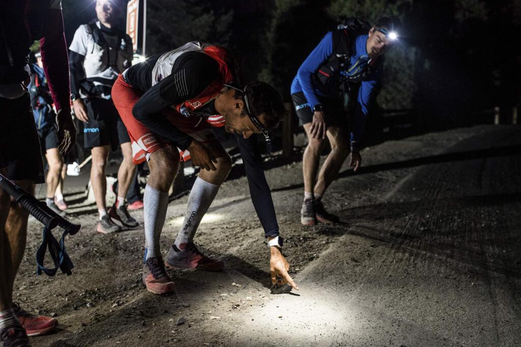 This Tuesday, Oct. 17, 2017, photo provided by Salomon shows professional trail runner Francois D'haene, left, at the completion of his journey, as he touches the Happy Isles Loop Road at the end of the John Muir Trail in Yosemite Valley, Calif. No one broke the three-day barrier until D'haene, one of the world's top trail runners, shattered the previous best time Oct. 17 by about 12 hours, finishing in less than 2 days and 20 hours. (Damien Rosso/DrozPhoto/Salomon via AP)