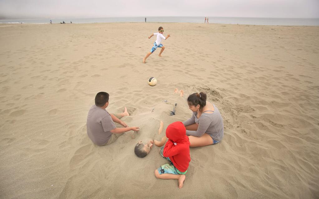 At Doran Beach Regional Park in Bodega Bay, Wednesday June 17, 2015, Luis and Maria Campos bury Custodio Campos with the help of Christopher Lugo, 6, in the Doran Beach Sand. Because of the drought, area beaches along the coast received high grades for cleanliness caused by less winter runoff. (Kent Porter / Press Democrat) 2015
