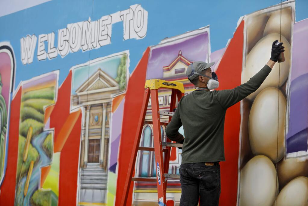 Mural artist Maxfield Bala applies spray paint to his 'Welcome to Petaluma' mural project on Petaluma Blvd South along Highway 101 in Petaluma on Monday, January 28, 2019. (BETH SCHLANKER/ The Press Democrat)