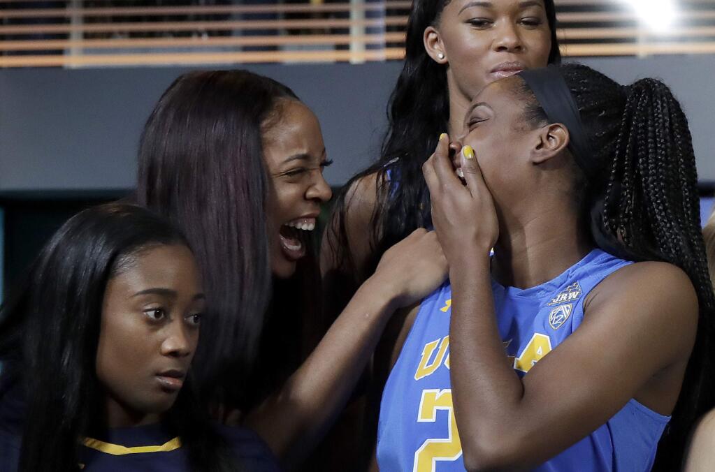 Cal's Kristine Anigwe, second from left, laughs with UCLA's Kennedy Burke while posing for group photos during NCAA college basketball Pac-12 media day in San Francisco, Wednesday, Oct. 10, 2018. Also pictured are UCLA's Lajahna Drummer, top, and California's Asha Thomas. (AP Photo/Jeff Chiu)