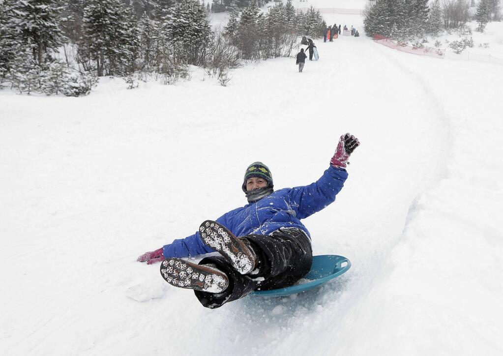 Patty Lang rides a snow disk down one of runs at the Adventure Mountian snow park near Echo Summit, Calif., Tuesday, Dec. 30, 2014. The California Department Water Resources held the first snow survey of the season near Echo Summit and found the snow pack to to be 21.3 inches deep. The water content of the snow measured Tuesday was about 33 percent of average. (AP Photo/Rich Pedroncelli)