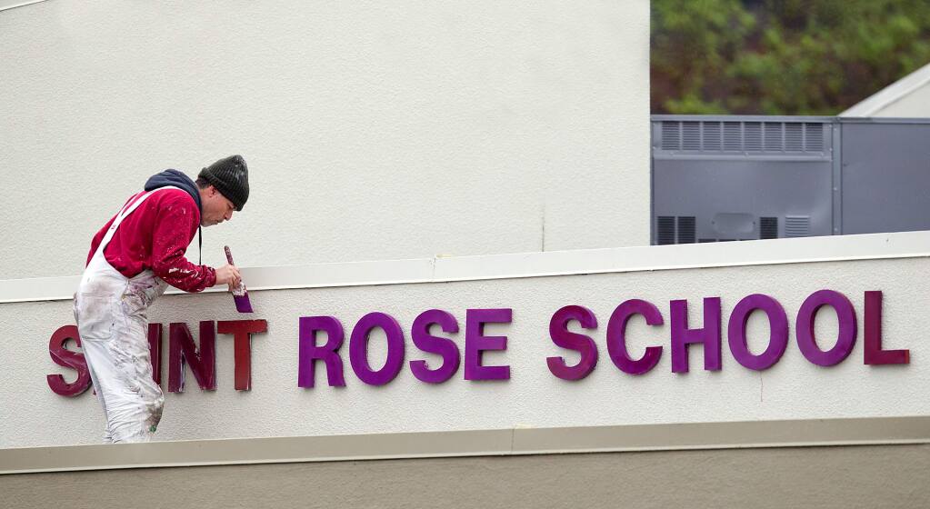 Workers repaint the sign at St. Rose School in Santa Rosa. The school survived the Tubbs fire, but over $1 million in damages occurred later when fire protection sprinklers flooded the school when they were re-pressurized. (photo by John Burgess/The Press Democrat)
