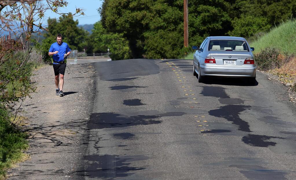 Matt Hughes runs along Faught Road, south of Shiloh Road, near Windsor. Faught Road has been on the list of county roads slated for repair. (CHRISTOPHER CHUNG / The Press Democrat)