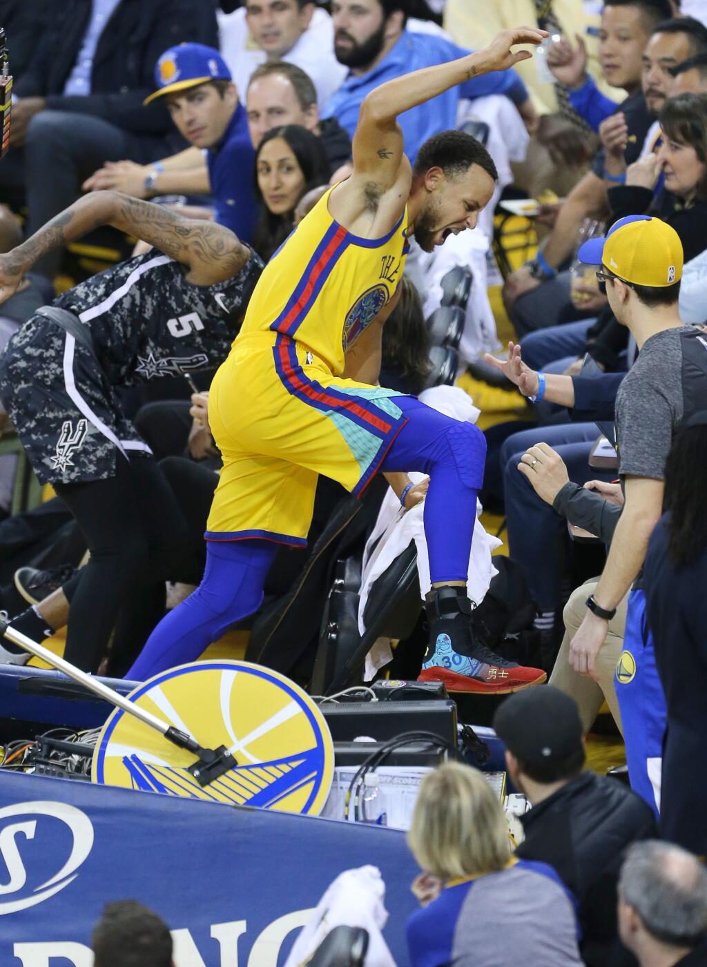 Golden State Warriors guard Stephen Curry winces in pain as he stumbles off the court on a play involving San Antonio Spurs' Dejounte Murray during their game in Oakland on Thursday, March 8, 2018. (Christopher Chung / The Press Democrat)