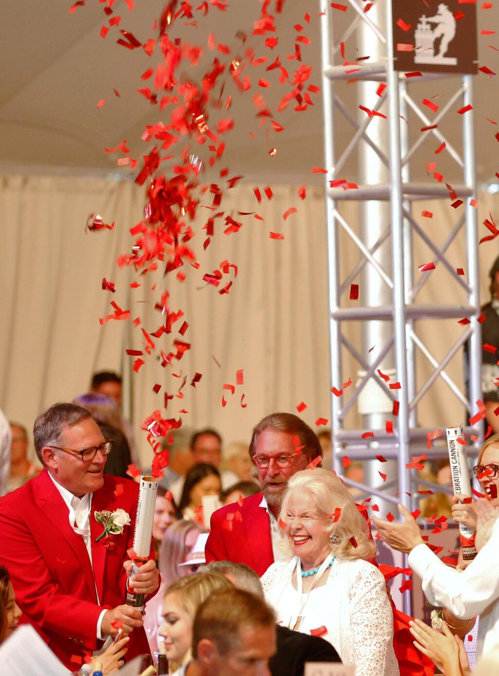 Michael Silacci, left, co-chair of the Hoopla Committee and winemaker at Opus One, shoots confetti in the air to celebrate with a winning bidder during Auction Napa Valley at Meadowood in St. Helena, California on Saturday, June 4, 2016. (Alvin Jornada / The Press Democrat)