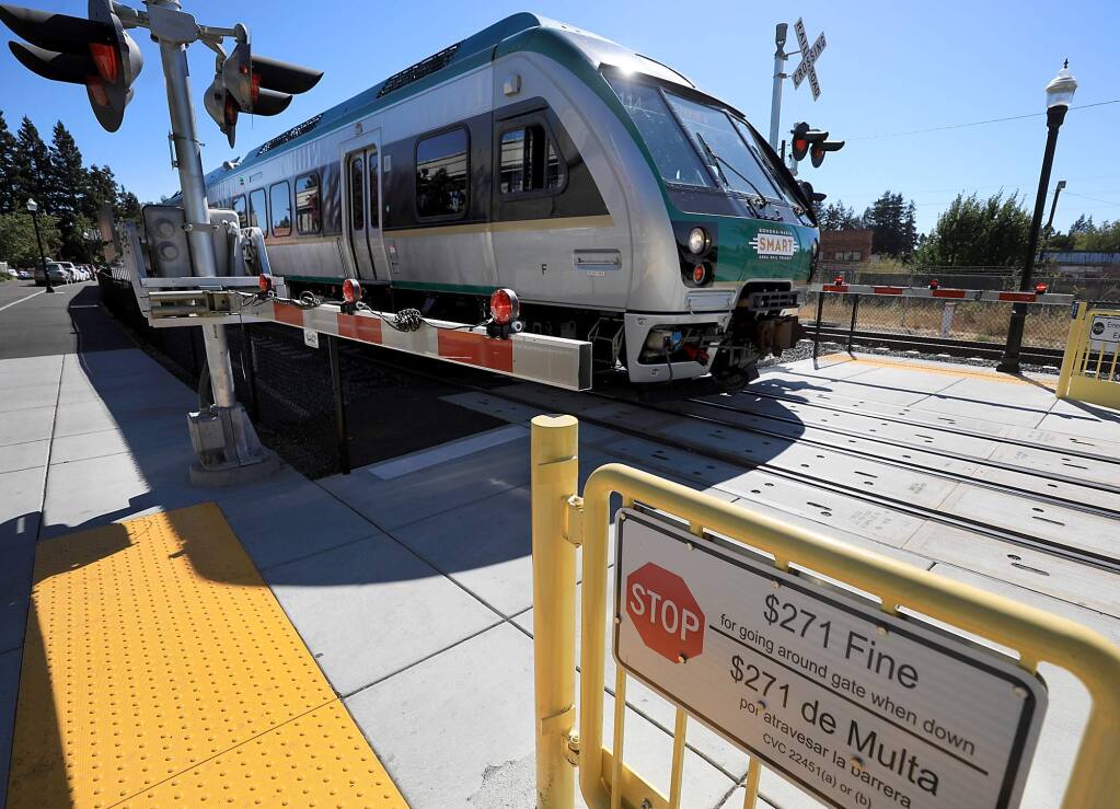 A pedestrian crossing arm is lowerd as a SMART train at the downtown Santa Rosa station in Railroad Square passes by, Monday, Sept. 10, 2018. (Kent Porter / The Press Democrat) 2018