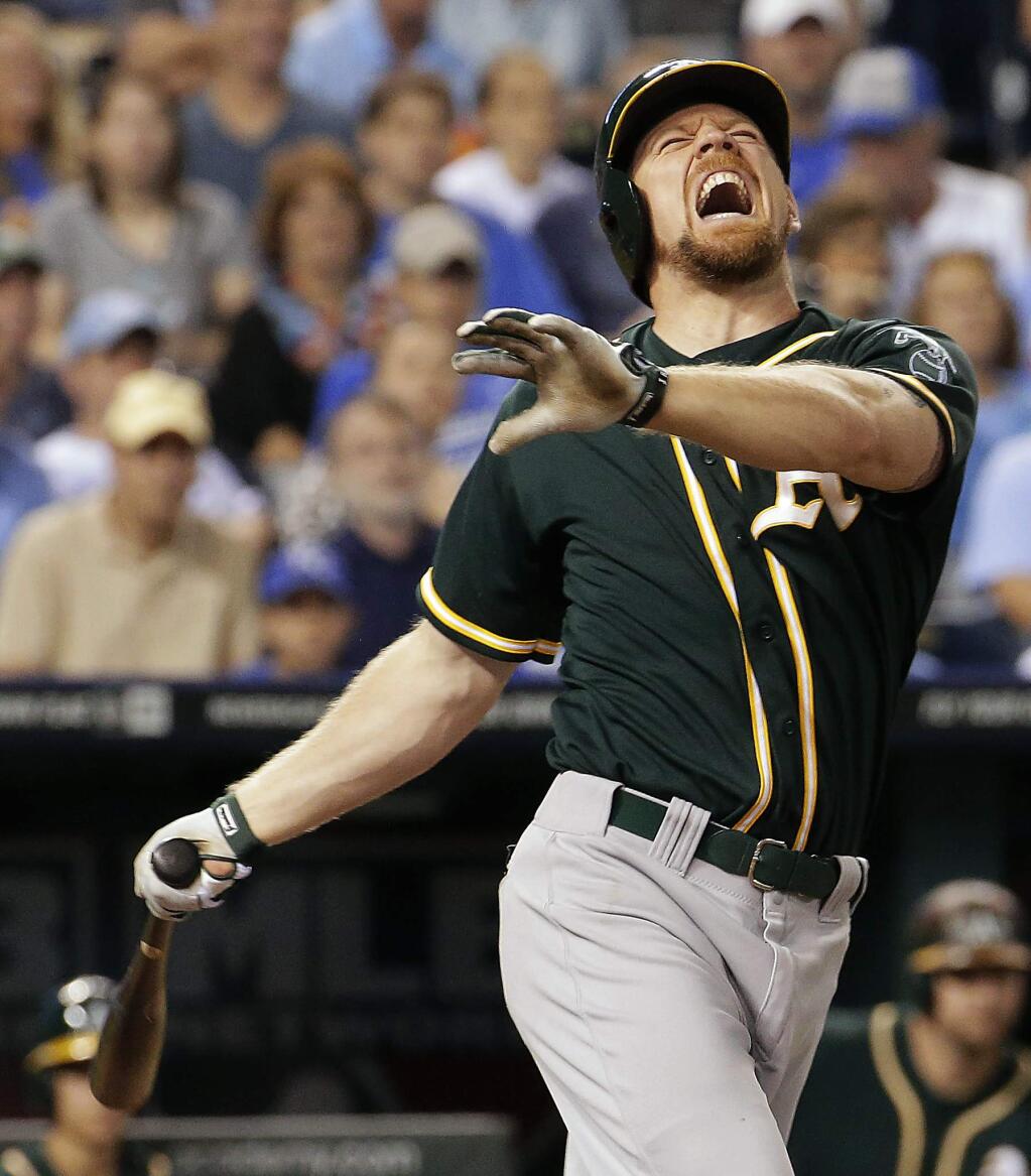 Oakland Athletics' Brandon Moss reacts after fouling a ball off his ankle during the sixth inning of a baseball game against the Kansas City Royals, Monday, Aug. 11, 2014, in Kansas City, Mo. (AP Photo/Charlie Riedel)