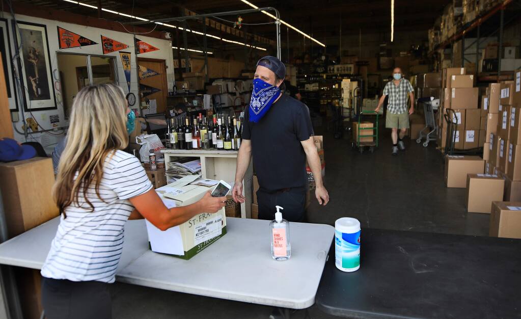 Diana Fox of Santa Rosa picks up her pre-ordered wine from Bottle Barn store manager Jason Schneider during Sonoma County's first day for curbside purchases for a variety of businesses Friday, May 8, 2020, in Santa Rosa. (Kent Porter / The Press Democrat) 2020