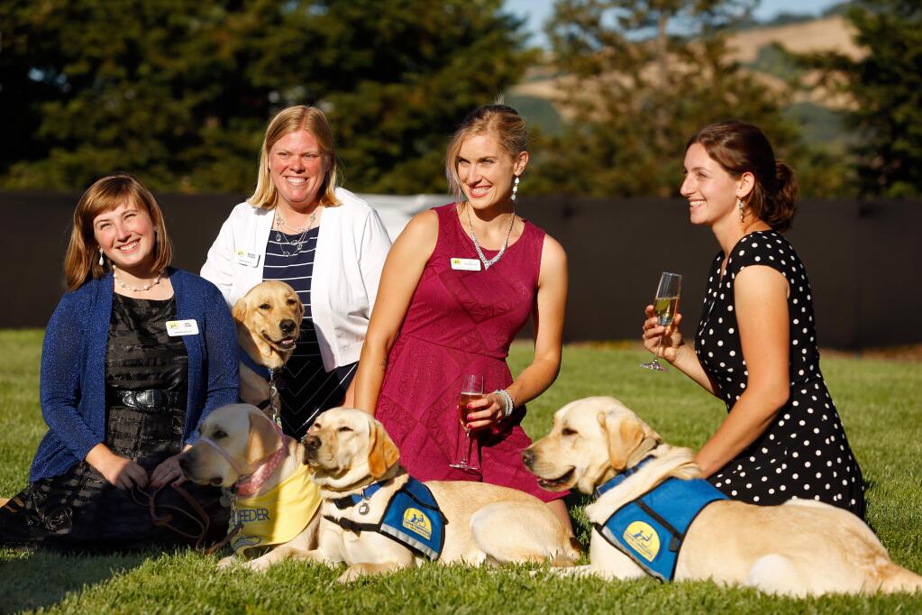 CCI apprentice instructors Ariel Vipond, left, Margaret Peterson, and Oz Robinson and CCI instructor Sarah Birman pose with a group of CCI dogs during the Sit Stay Sparkle gala Canine Companions for Independence in Santa Rosa, California on Saturday, June 18, 2016. (Alvin Jornada / The Press Democrat)