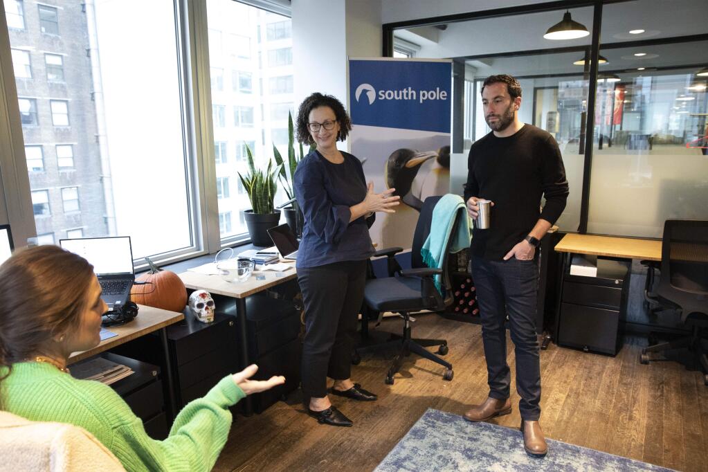 In this Tuesday, Nov. 5, 2019 photo, Erin Horleman, left, and Anne-Marie McGonnigal, with South Pole, meet with Lanny Grossman, owner of public relations firm EM50 Communications, at a WeWork office space in New York. WeWork is slashing the lavish spending that has fueled its breakneck growth while racking up unsustainable losses. Experts are skeptical that the office-sharing company can achieve meaningful cost reductions without somehow squeezing tenants. (AP Photo/Mark Lennihan)