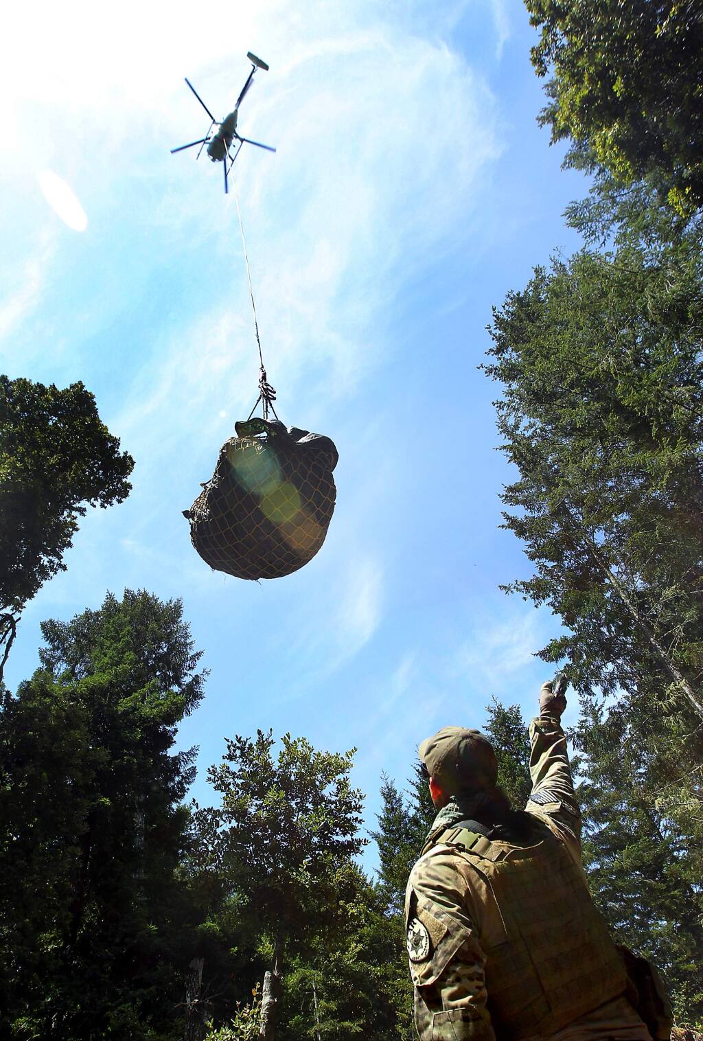 A member of the Lear Asset Management, who refused to give names in fear of retaliation, signals a helicopter leaving with a load of trash taken from a marijuana grow site in the Mendocino Redwood Co. land south of the town of Elk on Saturday, July 19, 2014. (JOHN BURGESS/ PD)