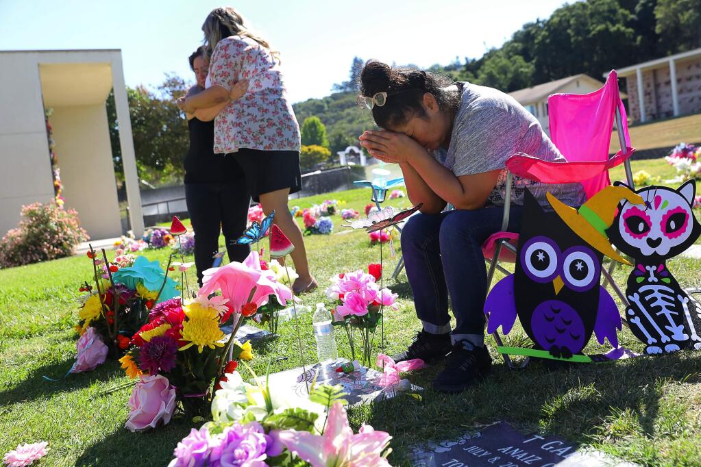 Dalia Ruiz, grandmother to Sayra and Delilah Gonzalez, weeps at their gravesite along with their aunts, Norma Gonzalez and Brandi Hernandez, at Calvary Catholic Cemetery, in Santa Rosa on Wednesday, September 27, 2017. The family members visited the cemetery after watching the children's mother, Alejandra Hernandez-Ruiz, appear in Sonoma County Court.(Christopher Chung/ The Press Democrat)