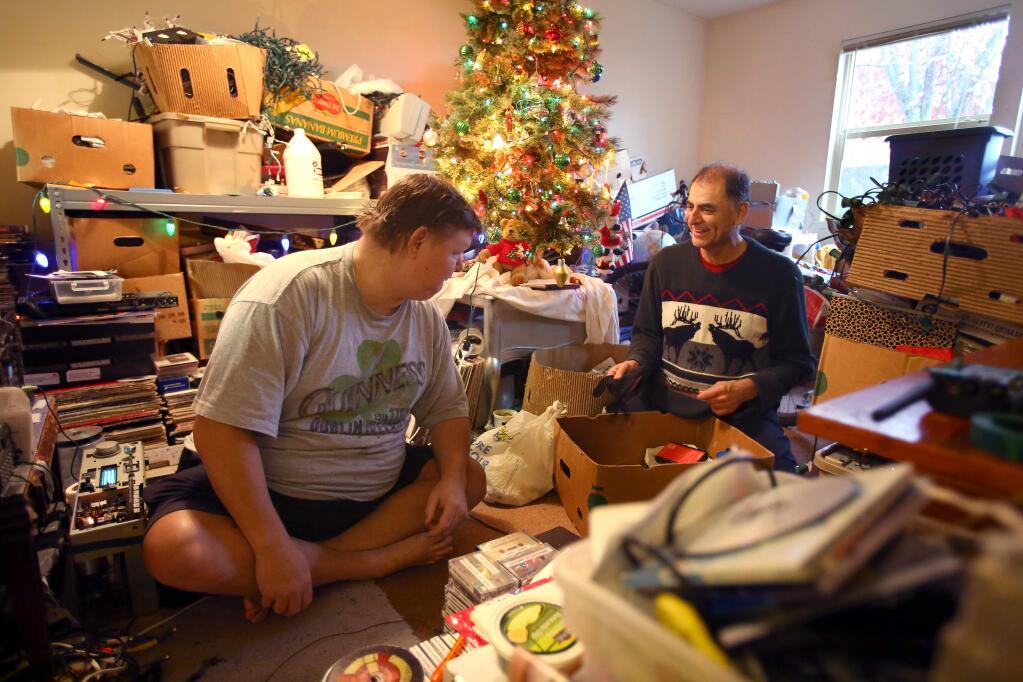 In-home caregiver Paul Esparza, right, negotiates what can be thrown out with his client, Jason Carlin, at Carlin's apartment in Rohnert Park on Friday, December 19, 2014. (Christopher Chung/ The Press Democrat)