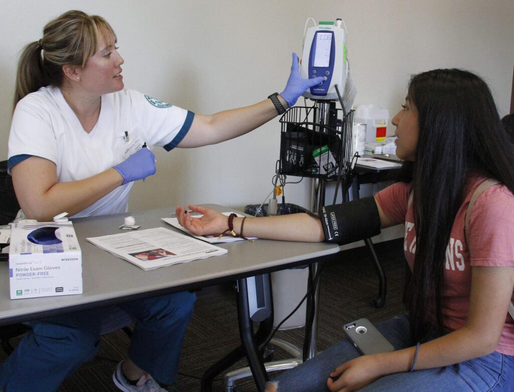 Bill Hoban/Index-Tribune. Lisa Kleman, left, a student nurse at Napa Valley College, takes 15-year-old Yurhizia Santiago‚'s blood pressure as part of the annual Sonoma Valley Comminity Health Center's Back to School Health Fair in 2017.