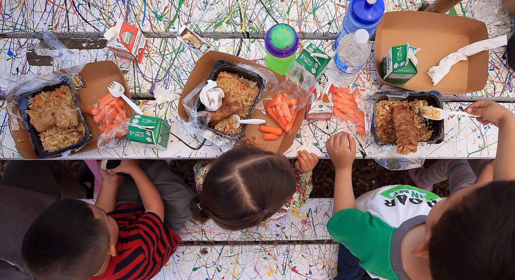 Children eat egg rolls and rice with carrots, milk and apple juice from the Redwood Empire Food Bank at Bayer Farm in Santa Rosa on June 5, 2017. The food bank will be providing children with free, healthy lunches at four Sonoma Valley locations this summer. (KENT PORTER/PD)