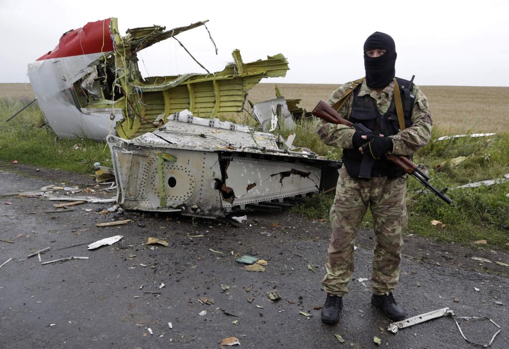 A Pro-Russian fighter stands guard at the site of a crashed Malaysia Airlines passenger plane near the village of Hrabove, Ukraine, eastern Ukraine Friday, July 18, 2014. Rescue workers, policemen and even off-duty coal miners were combing a sprawling area in eastern Ukraine near the Russian border where the Malaysian plane ended up in burning pieces Thursday, killing all 298 aboard. (AP Photo/Dmitry Lovetsky)