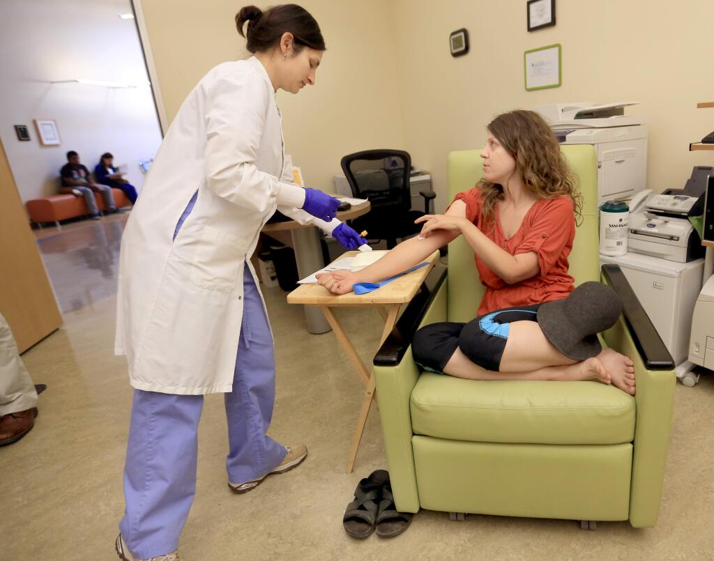 At the Petaluma Health Center, Elizabeth Barton of Petaluma has her blood drawn by phlebotomist Rebecca Alvarado. Barton waited for nearly three hours for the test as the Health Center helped her with paperwork from Medi-Cal on Wednesday, Aug. 8, 2014. (Kent Porter / Press Democrat) 2014