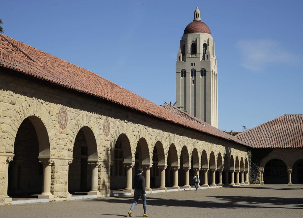 People walk on the Stanford University campus beneath Hoover Tower Thursday, March 14, 2019, in Stanford, Calif. (AP Photo/Ben Margot)