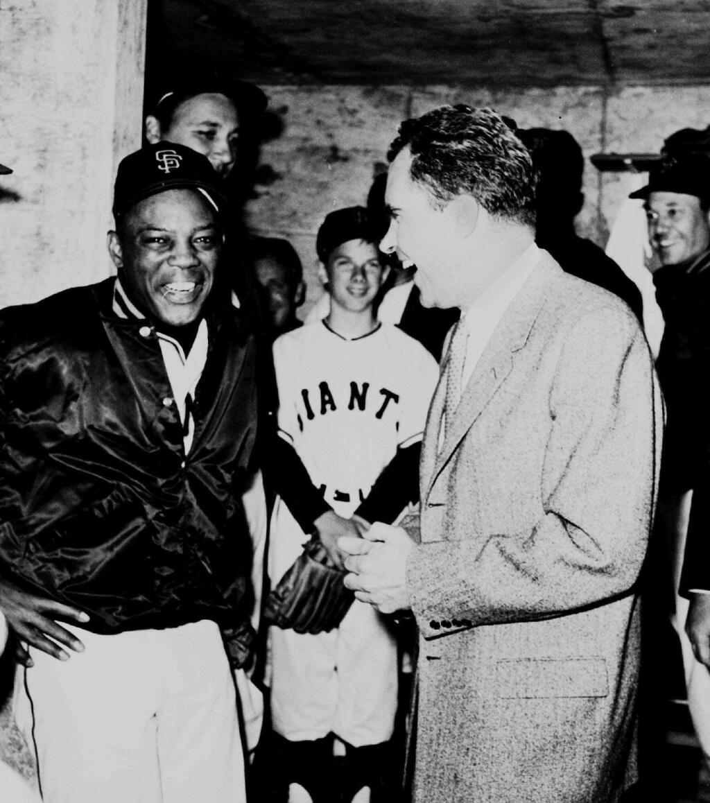 In this April 12, 1960 file photo San Francisco Giants outfielder Willie Mays, left, and Vice President Richard Nixon laugh in the Giants' dugout in San Francisco on April 12, 1960, prior to start of the San Francisco Giants' first regular-season game at Candlestick Park. Nixon threw out the ceremonial first pitch. (AP Photo/File)