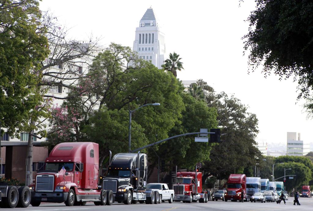 FILE - In this Friday, Nov. 13, 2009 file photo a caravan of trucks from the ports of Los Angeles and Long Beach, Calif., drive around Los Angeles City Hall during a protest against container fees being assessed against independent truckers. The California Trucking Association has filed what appears to be the first lawsuit challenging a sweeping new labor law that seeks to give wage and benefit protections to workers in the so-called gig economy, including rideshare drivers at companies such as Uber and Lyft. The federal lawsuit filed Tuesday, Nov. 12, 2019, contends that the legislation violates federal law and would deprive more than 70,000 independent truckers' of their ability to work. (AP Photo/Damian Dovarganes, File)