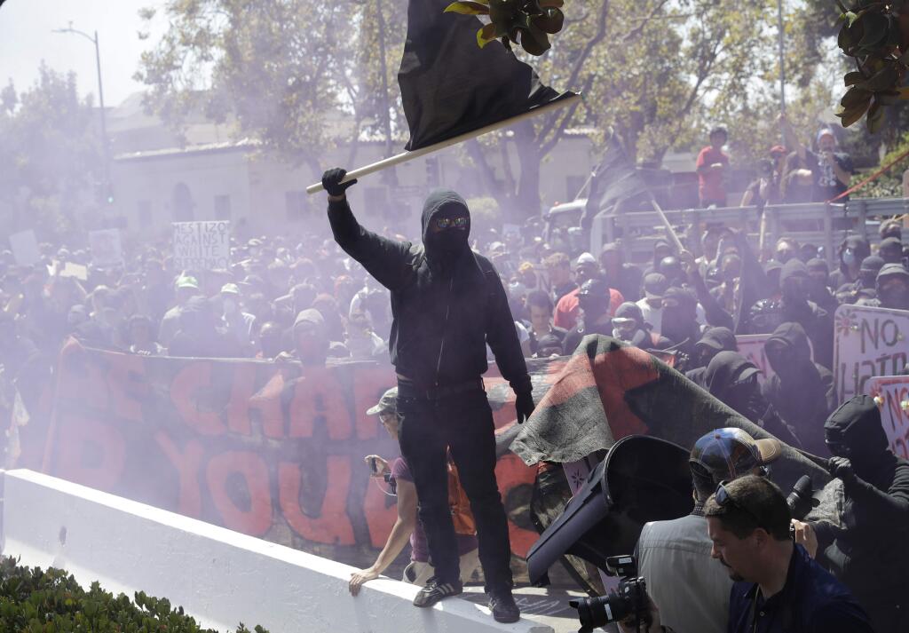 An anti-fascist demonstrator jumps over a barricade during a free speech rally Sunday, Aug. 27, 2017, in Berkeley, Calif. Several thousand people converged in Berkeley Sunday for a 'Rally Against Hate' in response to a planned right-wing protest that raised concerns of violence and triggered a massive police presence. Several people were arrested for violating rules against covering their faces or carrying items banned by authorities. (AP Photo/Josh Edelson)
