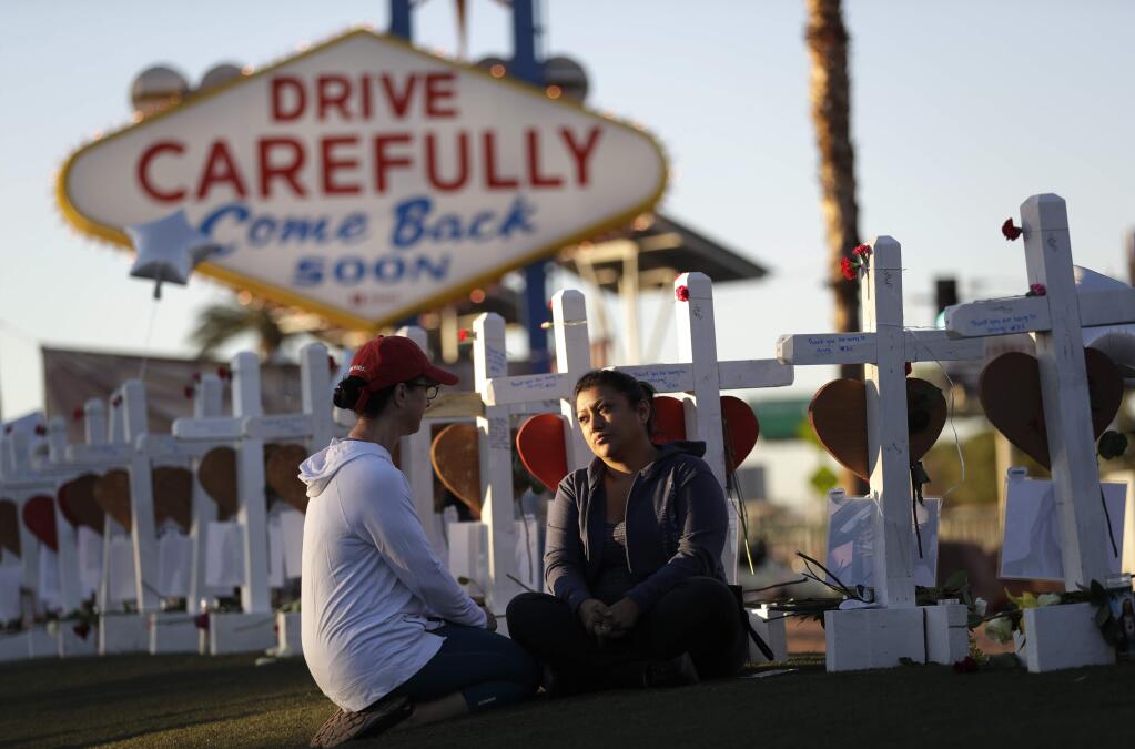 Shelley Boyle, left, and Cece Navarrette sit among crosses for those killed during the mass shooting Friday, Oct. 6, 2017, in Las Vegas. A gunman opened fire on an outdoor music concert on Sunday killing dozens and injuring hundreds. A cousin of Navarrette is among those killed. (AP Photo/Gregory Bull)