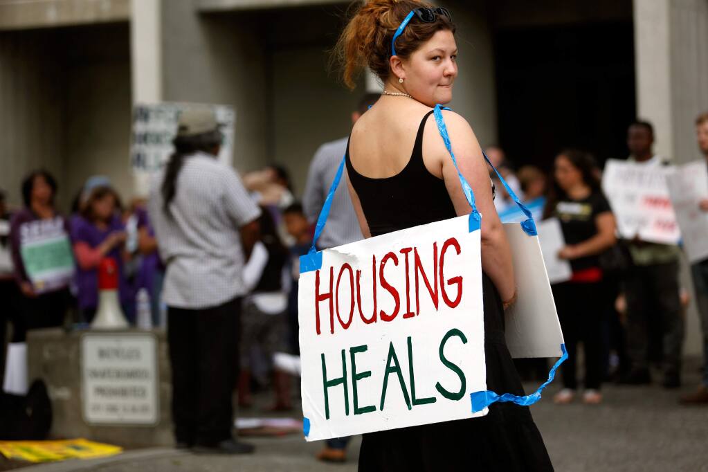 Eva Granahan carries a sign in support of affordable housing with a group of demonstrators outside the Santa Rosa city council chambers before a meeting to discuss rent control in Santa Rosa, California on Tuesday, May 3, 2016. (Alvin Jornada / The Press Democrat)